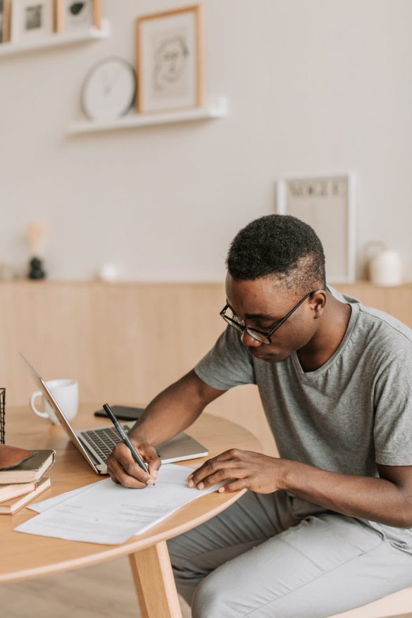 man in gray crew neck shirt studying and writing on white paper